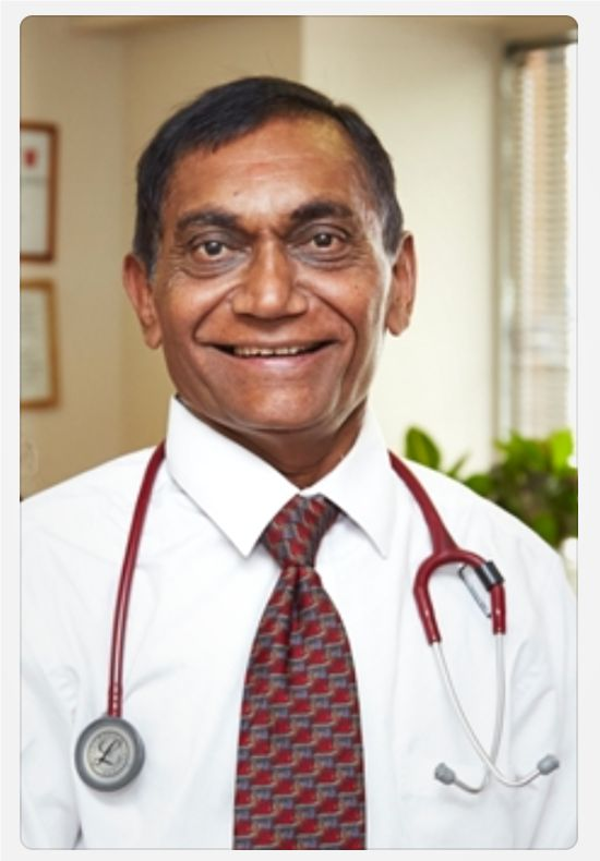 Portrait of Ashwin's dad in a white coat with a stethoscope around his neck